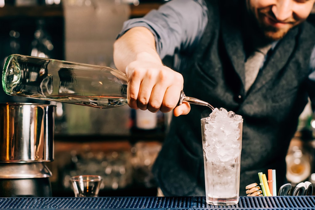 barman fabrique un cocktail avec du rhum et un verre